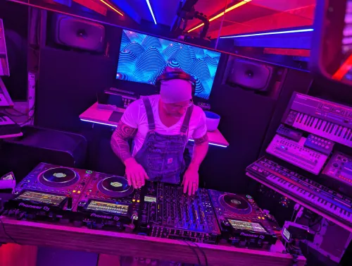 Phil Anthony performing on Pioneer DJ equipment in a studio bathed in pink and purple lighting