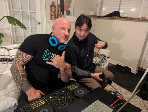 Phil Anthony and DJ Soo with portable DJ controller equipment doing a casual home recording session, one wearing a Seattle House Mafia t-shirt