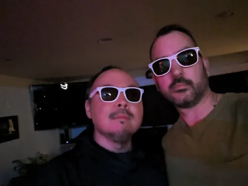 sangdo and Paul Velocity taking a selfie together wearing matching white sunglasses in a dimly lit room