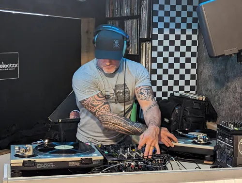 DJ focused on mixing at night club with Pioneer DJ equipment in dark lighting with blue accent lights