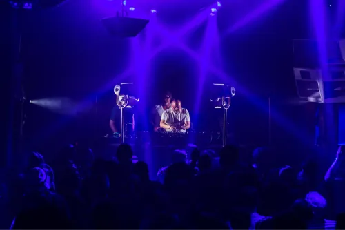 Seattle House Mafia performing on stage beneath violet light beams with a packed crowd in the foreground